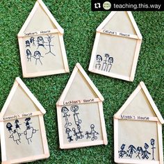 four wooden houses with drawings on them sitting in the grass next to eachother