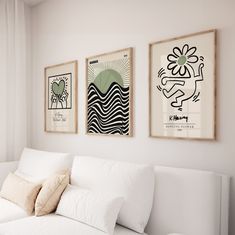 three framed art pieces hang on the wall above a white couch in a living room