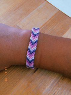 a woman's arm with a pink and blue chevron bracelet on top of it