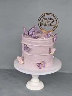 there is a pink cake with purple butterflies on it and a happy birthday sign in the middle