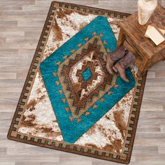 a blue and brown rug on the floor next to a wooden table with a vase