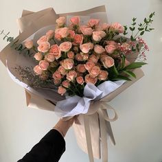 a person holding a bouquet of pink roses