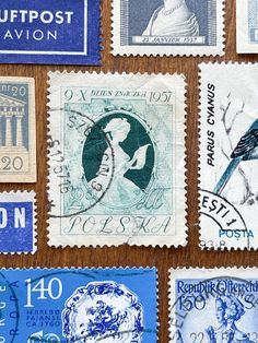 several different postage stamps on a wooden surface