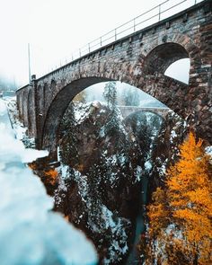 an old stone bridge with snow on the ground