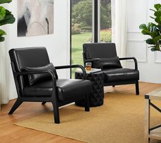 two black leather chairs sitting on top of a wooden floor next to a coffee table