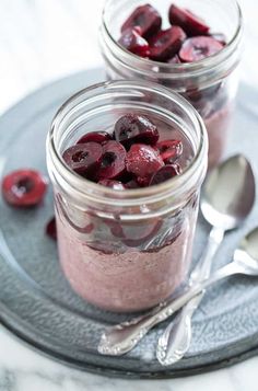 two mason jars filled with raspberry chia pudding and spoons on a plate