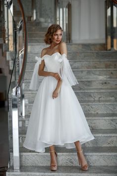 a woman in a white dress standing on stairs