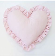 a pink heart shaped pillow with ruffles on the bottom and sides, against a white background