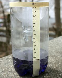 a measuring tape on top of a water bottle with blue liquid in it and trees in the background