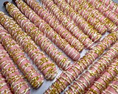 pink and gold decorated cookies are lined up on a baking sheet with sprinkles