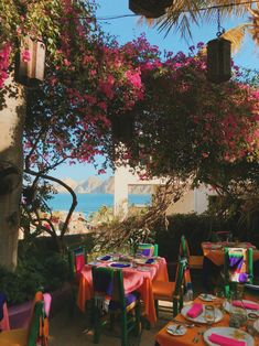 an outdoor dining area with colorful tables and chairs, overlooking the ocean on a sunny day