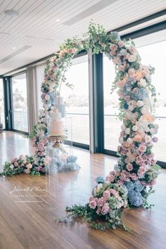 a wedding cake and flowers on the floor in front of large windows with glass doors