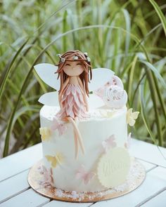 a cake decorated with a fairy sitting on top of it