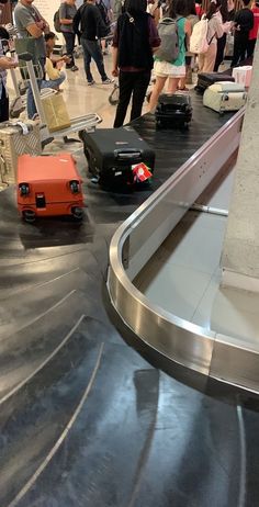 luggage sitting on top of an airport baggage claim conveyor belt with people standing around