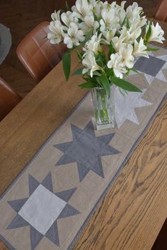 a vase filled with white flowers sitting on top of a wooden table