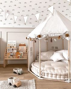 a white tent bed sitting in a bedroom next to a wooden table