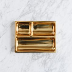 two gold trays on a marble surface