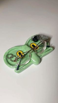 a pair of glasses sitting on top of a green frog keychain with yellow eyes