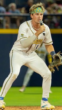 a baseball player holding a microphone on top of a field