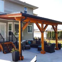 a covered patio with couches and chairs in front of a house on a sunny day