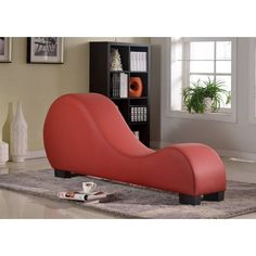 a red chaise lounger sitting on top of a rug in a living room