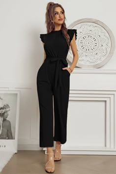 Our Ylika Jumpsuit comes in a solid black colour. Breaking out from the walls of your workroom, this sleeveless style pantsuit can take you from the office to a formal party with its ruffle collar, ankle length hem and self tie fabric waist belt. Make the stares worthwhile by pairing this with pair of our strappy heels and a mini leather bag with a pop of neon shade! Size Guide: Iris is 5’7” tall, and has a 35.4” bust, 23.9” waist, & 35.2” hips. She is wearing a S / US 4 / AU 8. This dress is tr Outfit Formal Mujer, Holiday Party Fashion, Look Office, Long Jumpsuit, Solid Jumpsuit, Look Formal, High Neck Sleeveless, Long Jumpsuits, Black Sleeveless