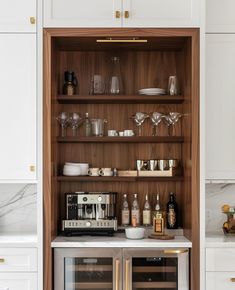 a kitchen with white cabinets and marble counter tops, including a wine cooler in the middle