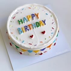 a birthday cake with white frosting and colorful sprinkles