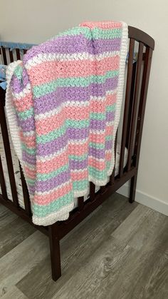 a crocheted blanket is draped over a wooden crib