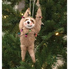 a stuffed slotty hanging from a christmas tree with lights on it's head