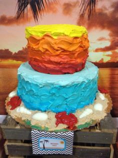 a multi colored cake sitting on top of a wooden crate next to a palm tree