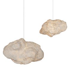 two rock like objects suspended from strings on a white background