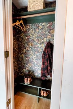 an open closet with shoes and coat hanging on the wall, next to a pair of slippers