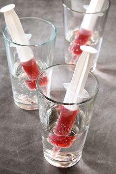 three glasses filled with liquid and toothbrushes on top of a table next to each other