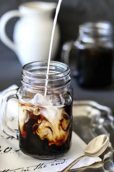 a glass jar filled with liquid sitting on top of a table next to spoons