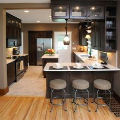 a kitchen with wooden floors and black cabinets