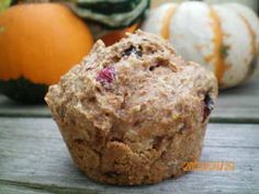 a muffin sitting on top of a wooden table next to pumpkins and gourds