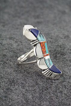 This turquoise, lapis, opalite and sterling silver inlay ring was made by Navajo silversmith James Manygoats. The back is stamped R.B. and .925.Size: 5.5Length: 1 1/2"Width: 1/2"Free shipping on all orders! We ship with USPS and always include tracking. All orders ship within a day of payment.Returns are accepted up to 30 days after you receive your order. Just send us a message. Our shop offers cash back or store credit. The item must be returned in the same condition. Southwestern Sterling Silver Opal Ring, Collectible Blue Inlay Rings, Unique Sterling Silver Opal Inlay Ring, Unique Sterling Silver Opal Ring With Inlay, Multi Stone, Native American Jewelry, Free Jewelry, Turquoise, Sterling Silver