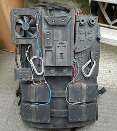 the back end of a large piece of luggage with multiple wires attached to it and two people standing in the background