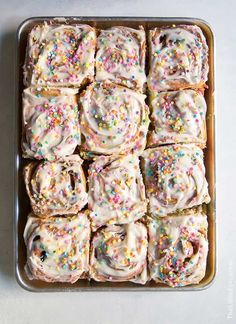 a pan filled with frosted donuts covered in sprinkles