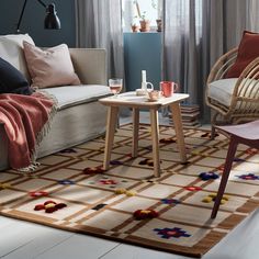 a living room filled with furniture and a rug on top of a wooden floor next to a window