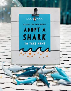 a sign that says adopt a shark to take home on a table with blue and white toothbrushes