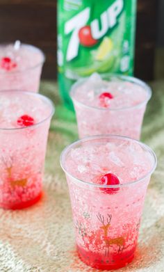 three cups filled with pink liquid next to a can of soda