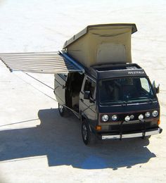 an suv is parked in the sand with its awning open