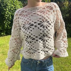 a woman wearing a white crochet top standing in the grass