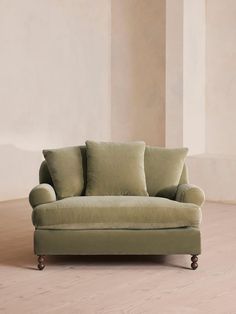 a green couch sitting on top of a hard wood floor next to a white wall