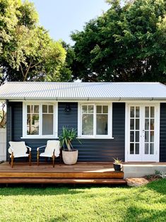 a small blue house with two chairs on the porch