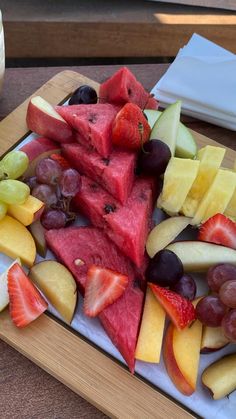 there is a platter of fruit that includes watermelon, apples, grapes and strawberries