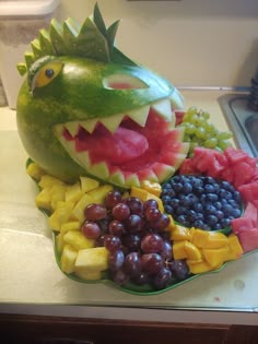 a watermelon shaped like a dragon with grapes and melons in it's mouth