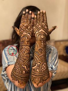 a woman holding her hands up to her face with hendi designs on it's palms